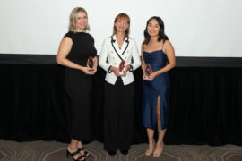 Three women stand side by side holding awards.